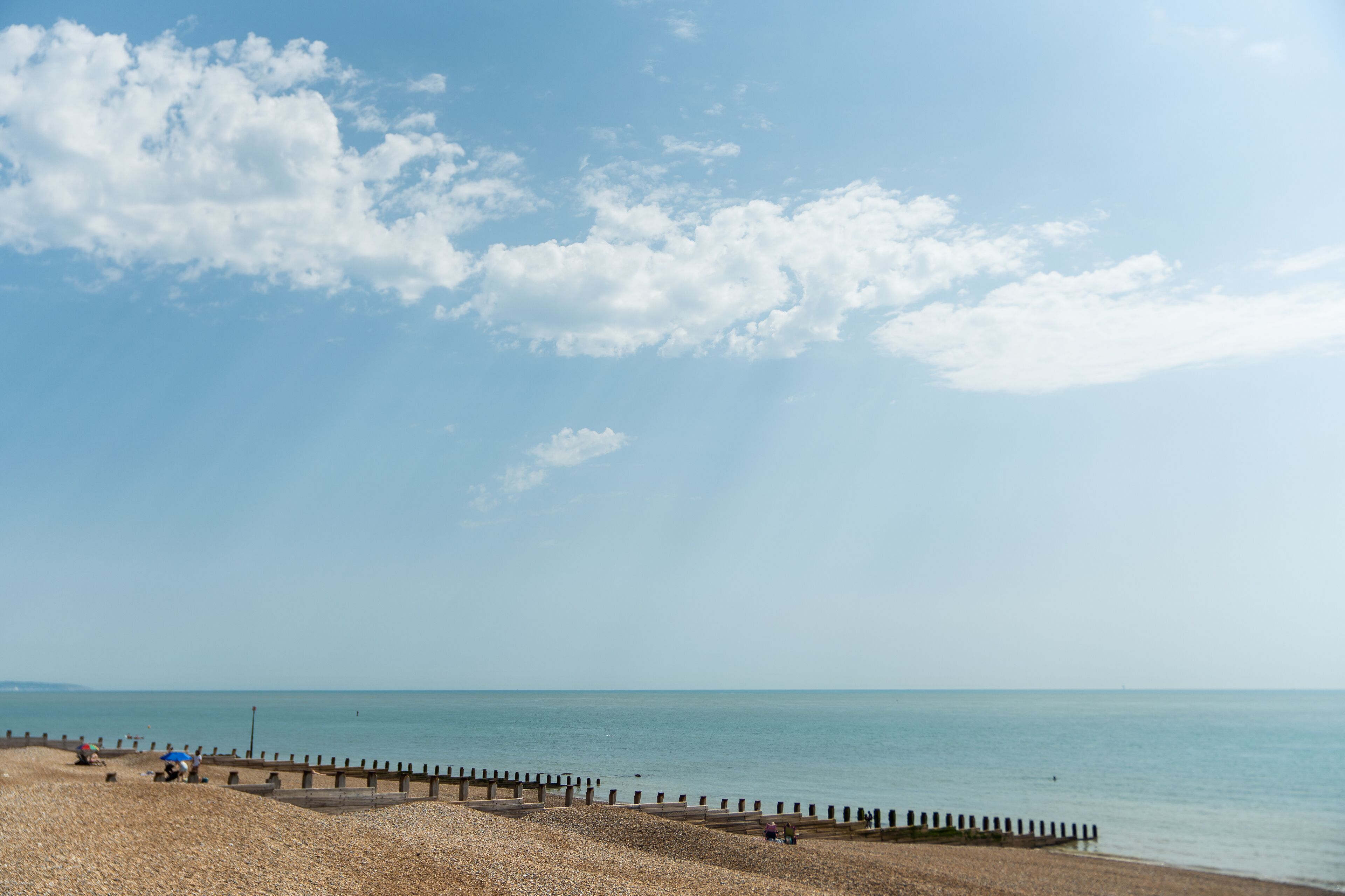 A beach with a wooden jetty and a clear sky.