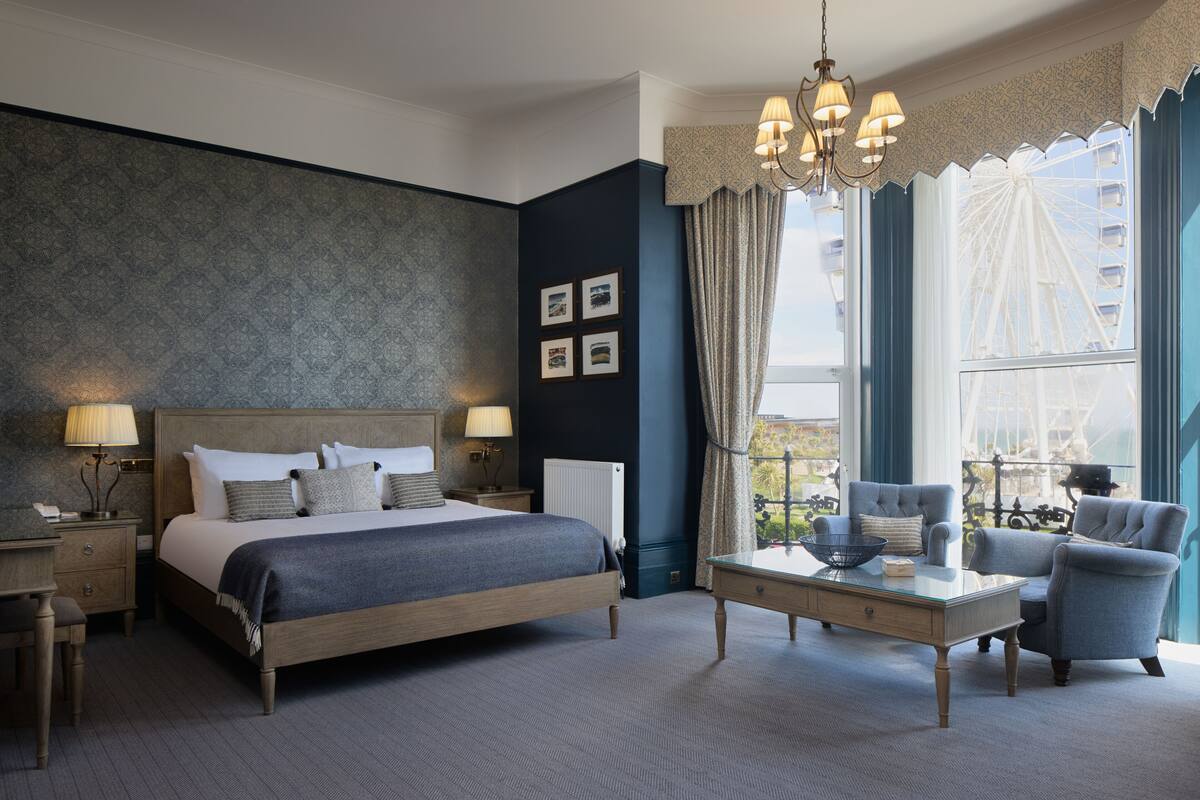 Habitación de hotel moderna con una cama grande, un escritorio, una silla y vistas a una noria.