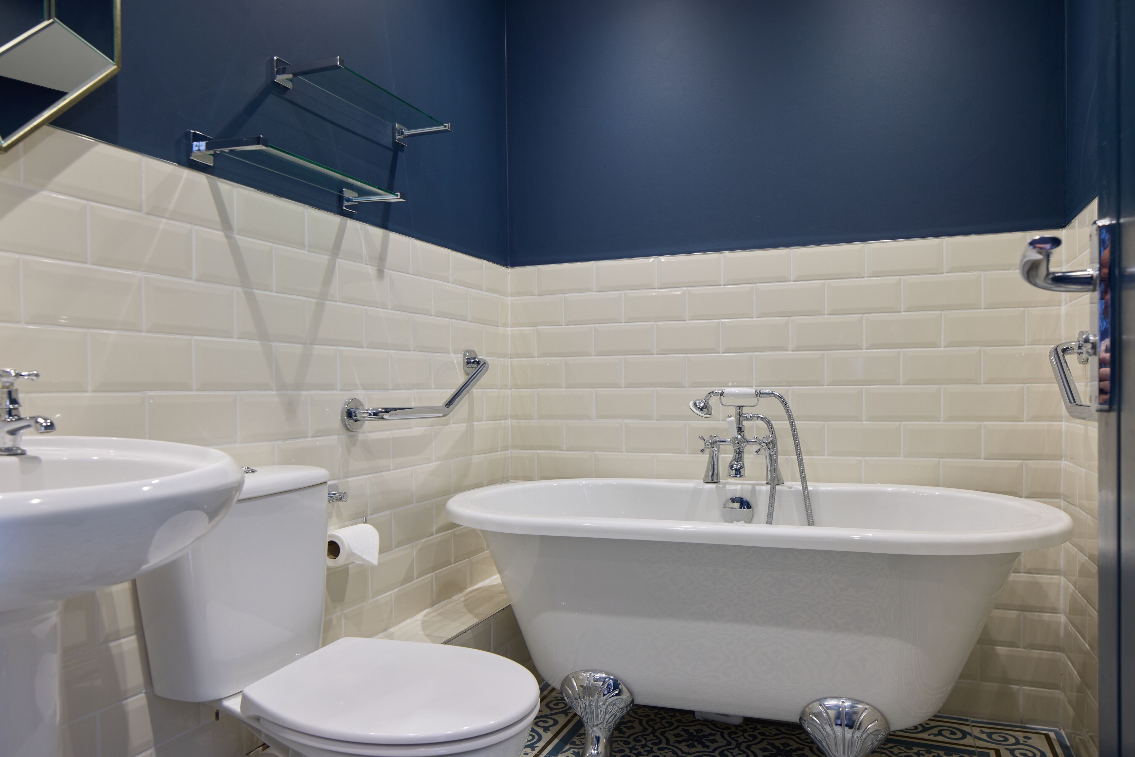 A bathroom with a white toilet, a white sink, and a white freestanding bathtub.