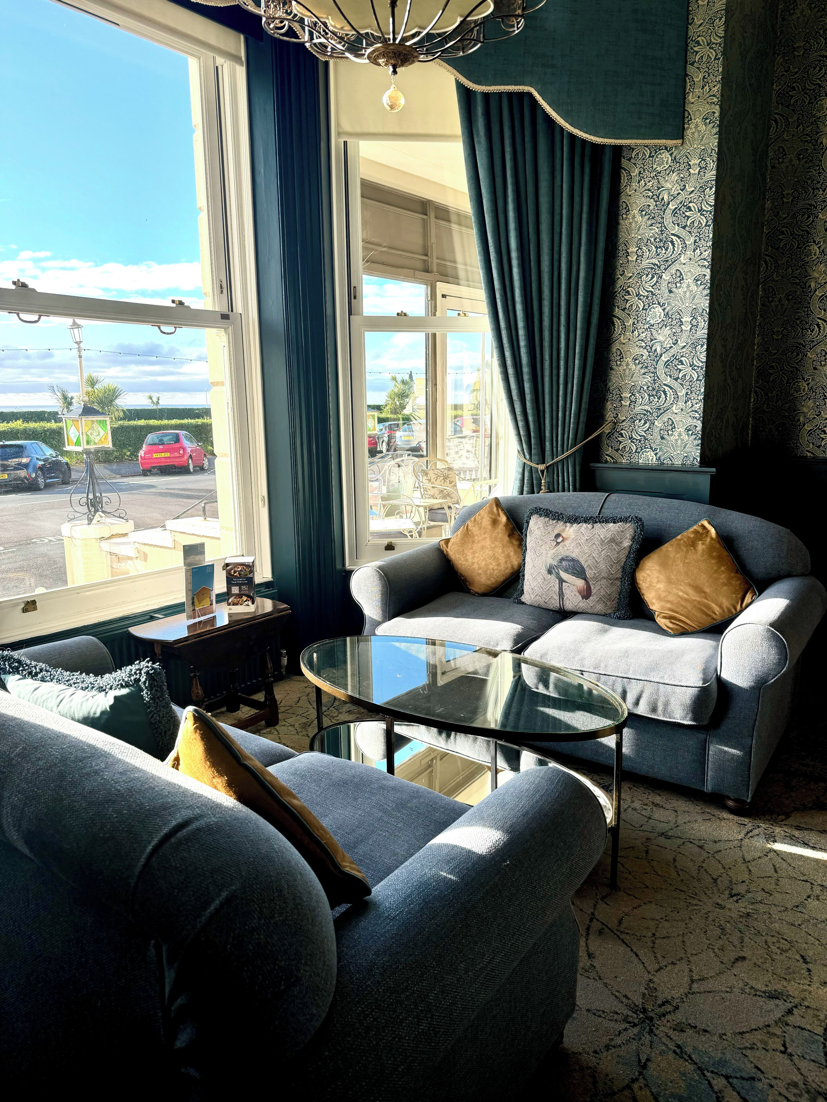 A modern living room with a sofa, a glass coffee table, and a view of the street outside.