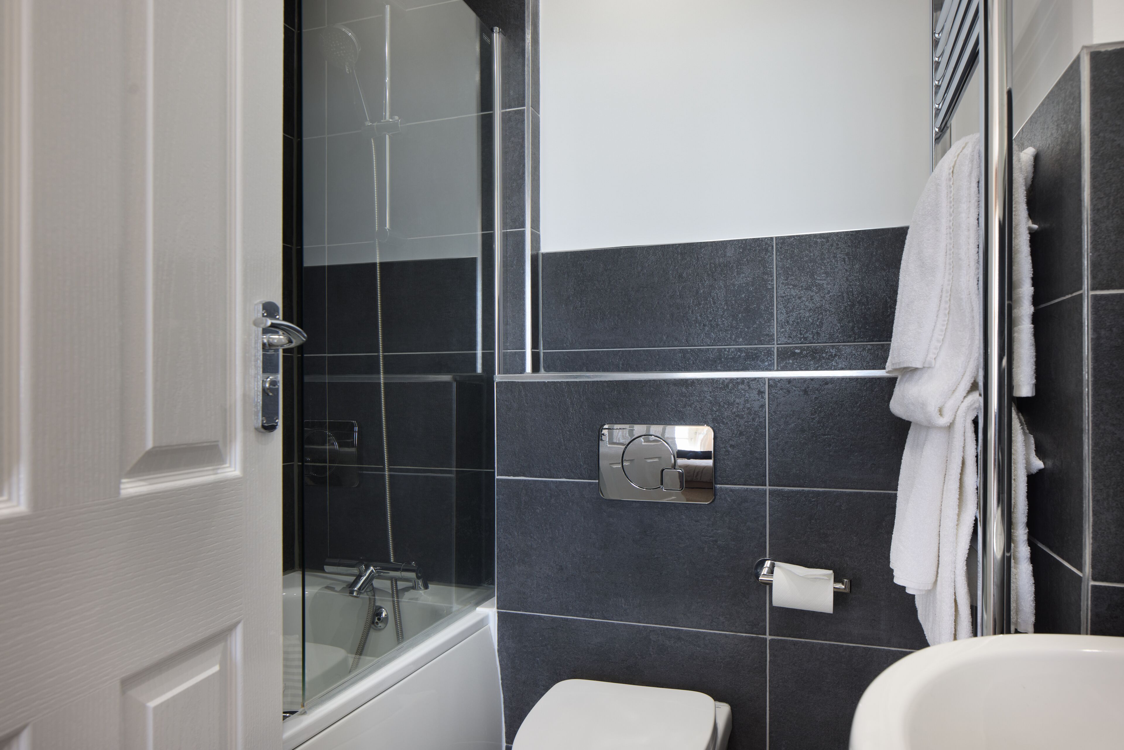 Un baño moderno con cabina de ducha de vidrio, inodoro blanco y un perchero para toallas.