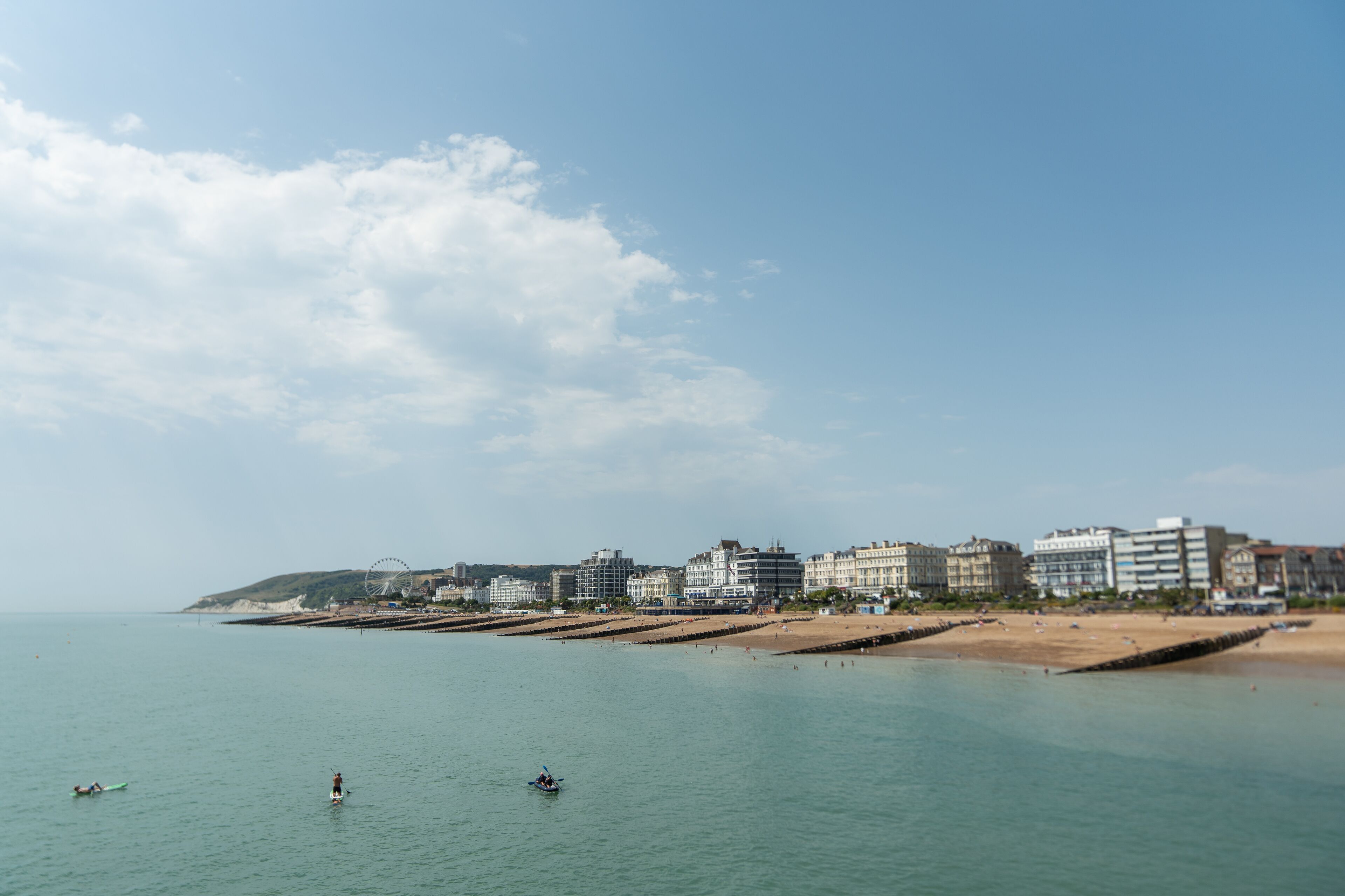 A coastal cityscape with a beach, buildings, and a clear sky.