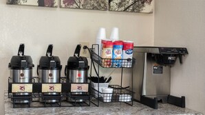 A coffee station with three Bunn coffee makers, a hot water dispenser, and a coffee machine with disposable cups and sachets. - Red Roof Inn Cincinnati East - Beechmont (Cincinnati)