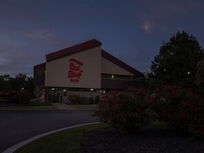 Punainen Red Roof Inn -hotellirakennus, jossa on selkeästi näkyvä punainen logo, tasakatto ja yksinkertainen julkisivu.