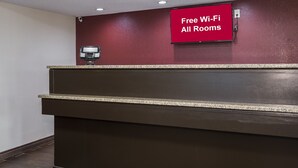 A reception desk with a 'Free Wi-Fi All Rooms' sign, a security camera, and a card reader. - Red Roof Inn Cincinnati East - Beechmont (Cincinnati)