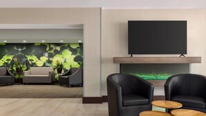 Un hall con un conjunto de sofás, dos sillones de cuero y un televisor de pantalla plana sobre una chimenea.