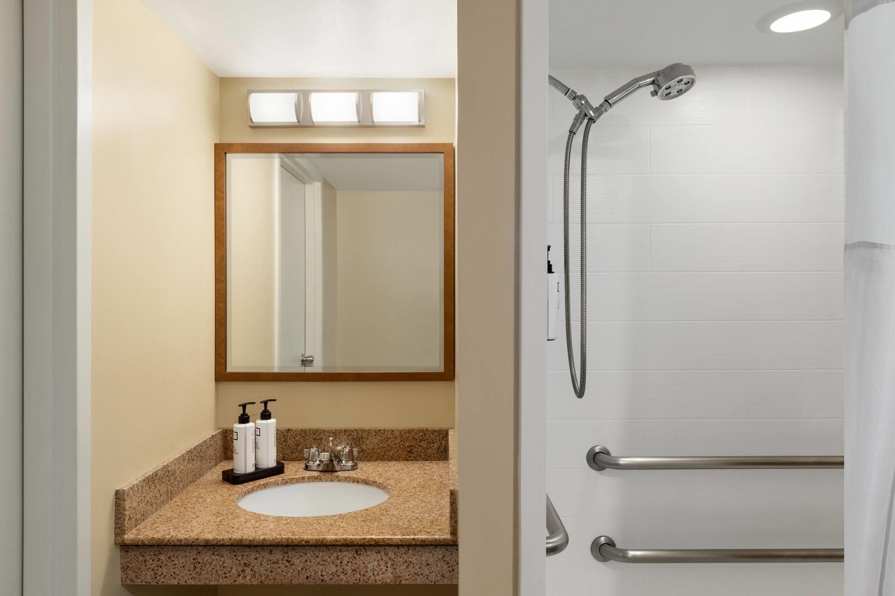 Un baño con lavamanos, espejo y ducha.