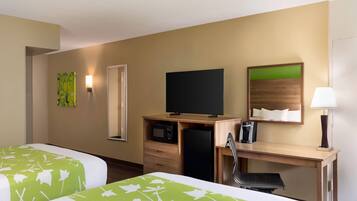 Habitación de hotel con dos camas, un escritorio, televisor, microondas, refrigerador, una silla y una lámpara.