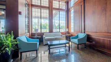 A lobby with a large window, a sofa, two armchairs, a coffee table, and a potted plant.