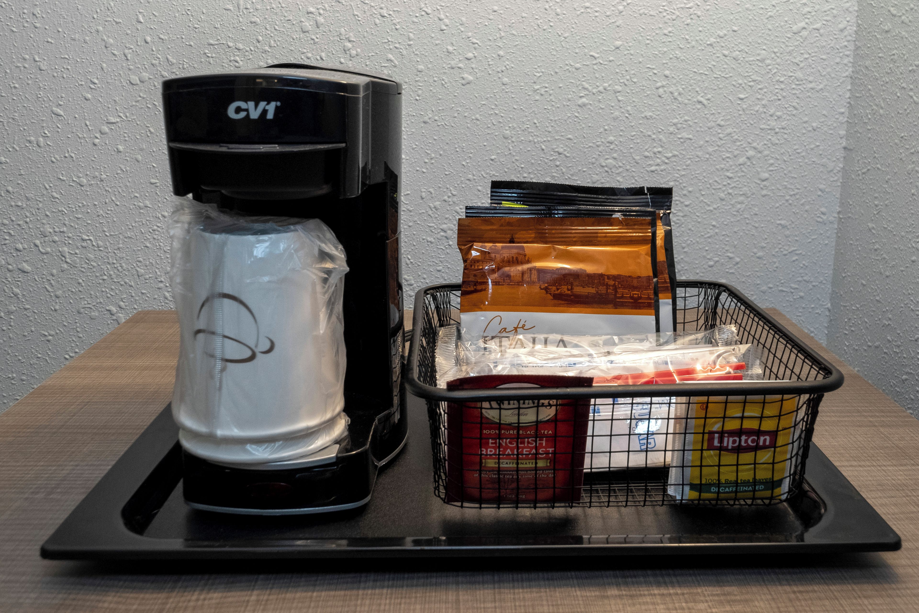 Une machine à café et un panier contenant divers objets, le tout posé sur un plateau.