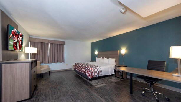 Une chambre d’hôtel équipée d’un lit, d’un bureau, d’une chaise et d’un téléviseur fixé au mur.