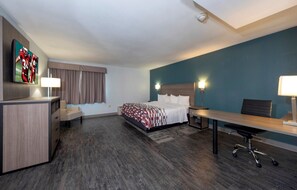 Une chambre d’hôtel équipée d’un lit, d’un bureau, d’une chaise et d’un téléviseur fixé au mur.