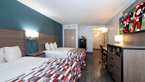 A hotel room with two beds, a desk, a TV, and a microwave.