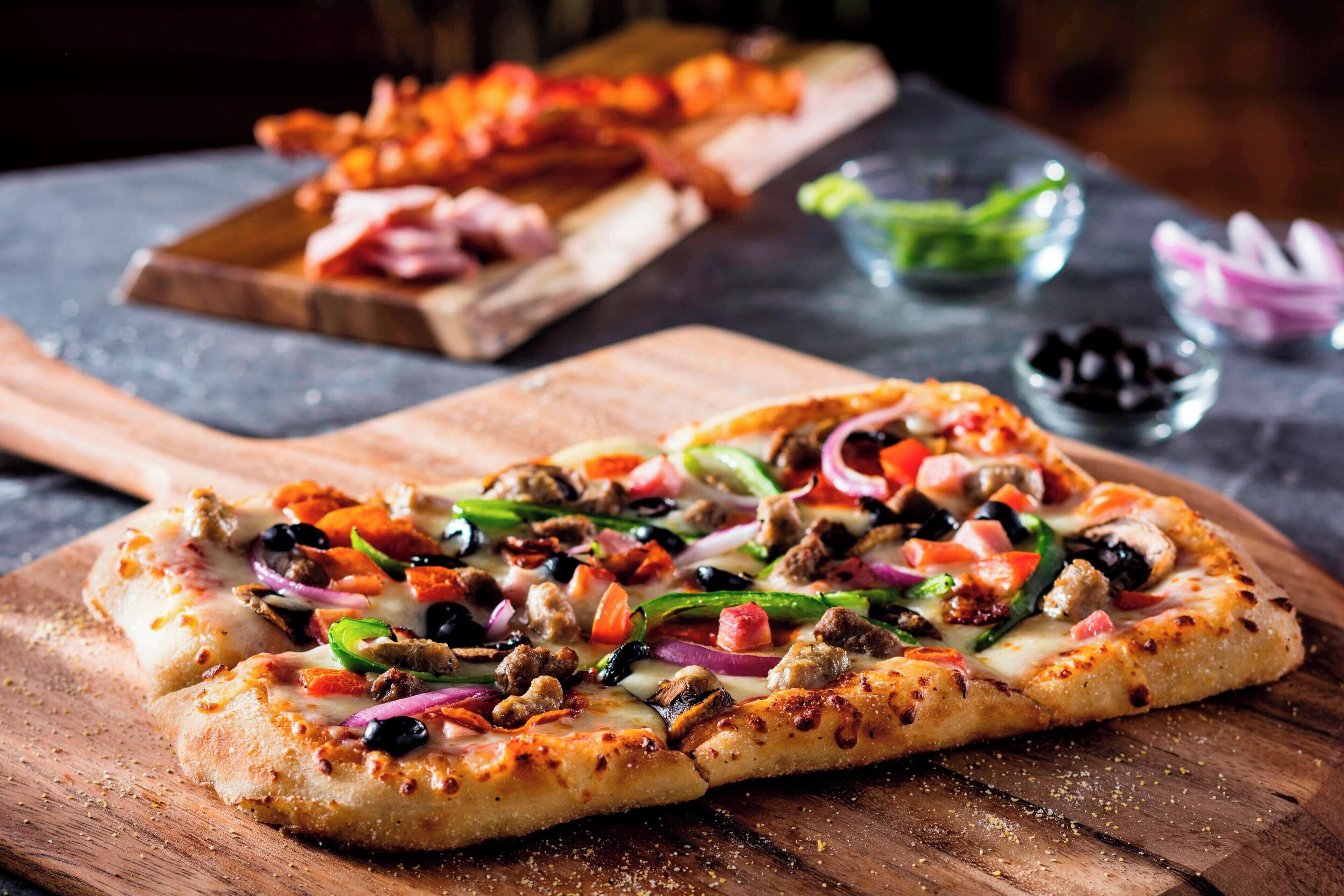 A pizza with various toppings on a wooden board.
