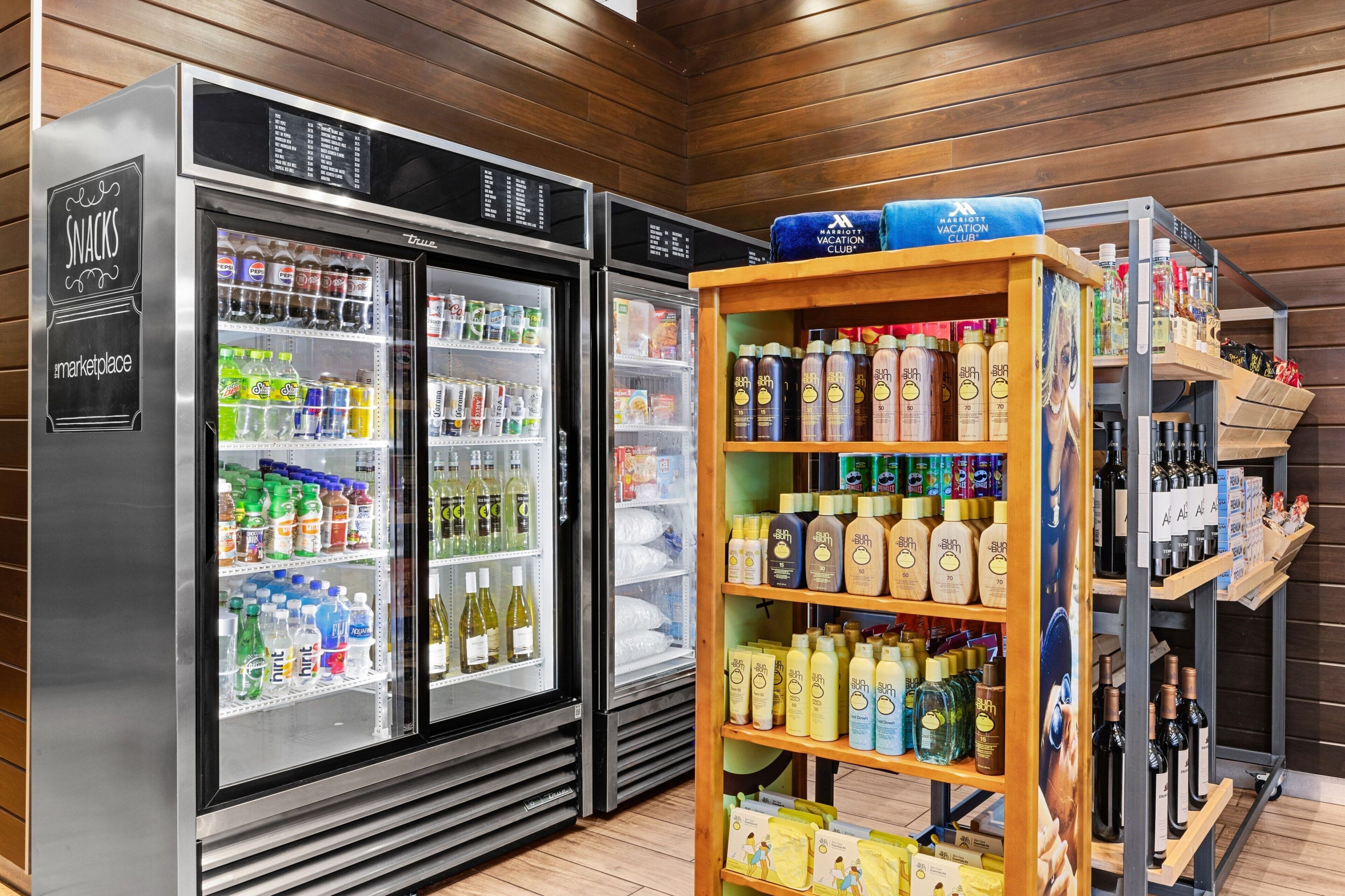 A minibar area with two refrigerators stocked with beverages and a shelf with alcohol bottles.