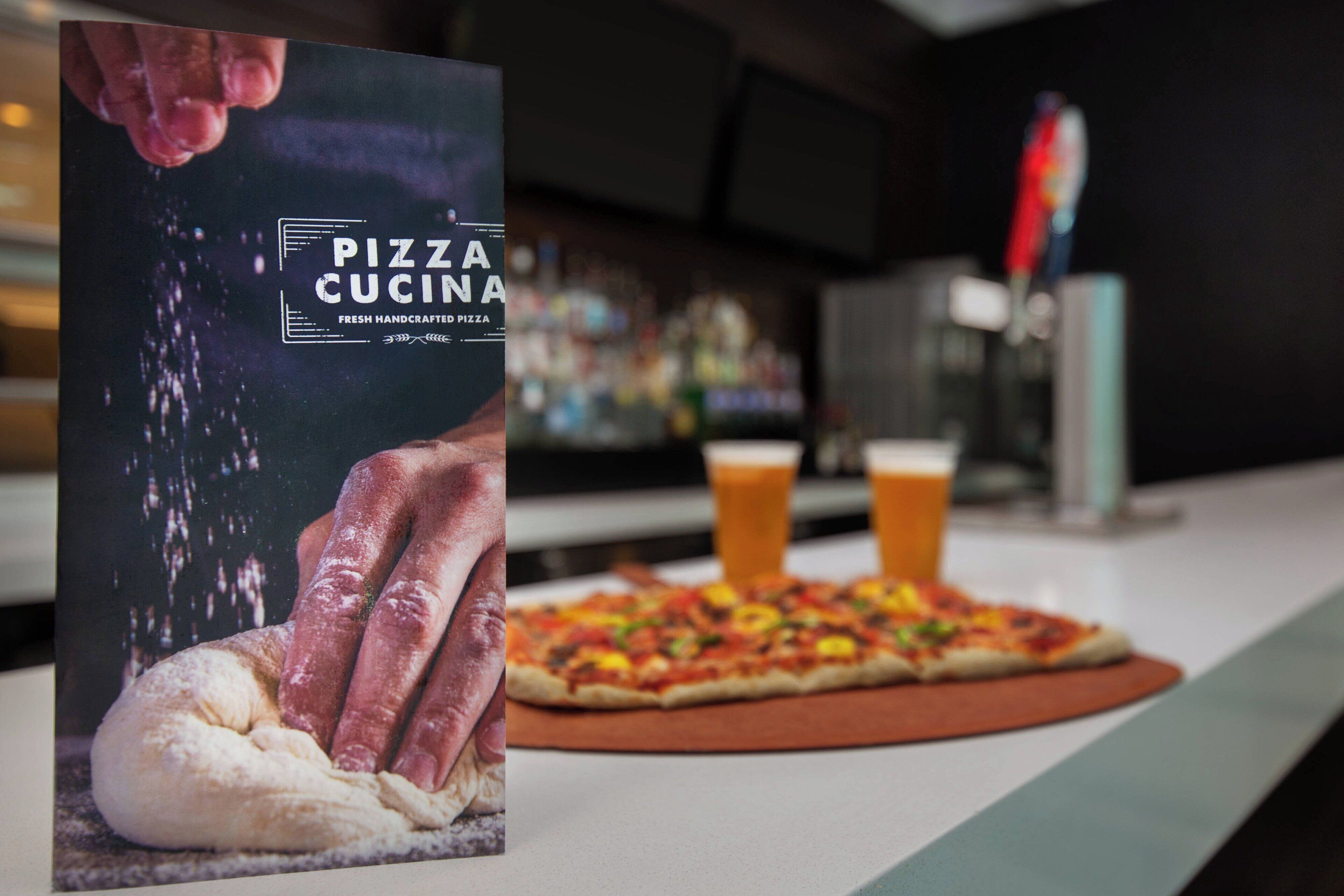 Una pizzería con un cartel que muestra una pizza y una mano amasando masa.
