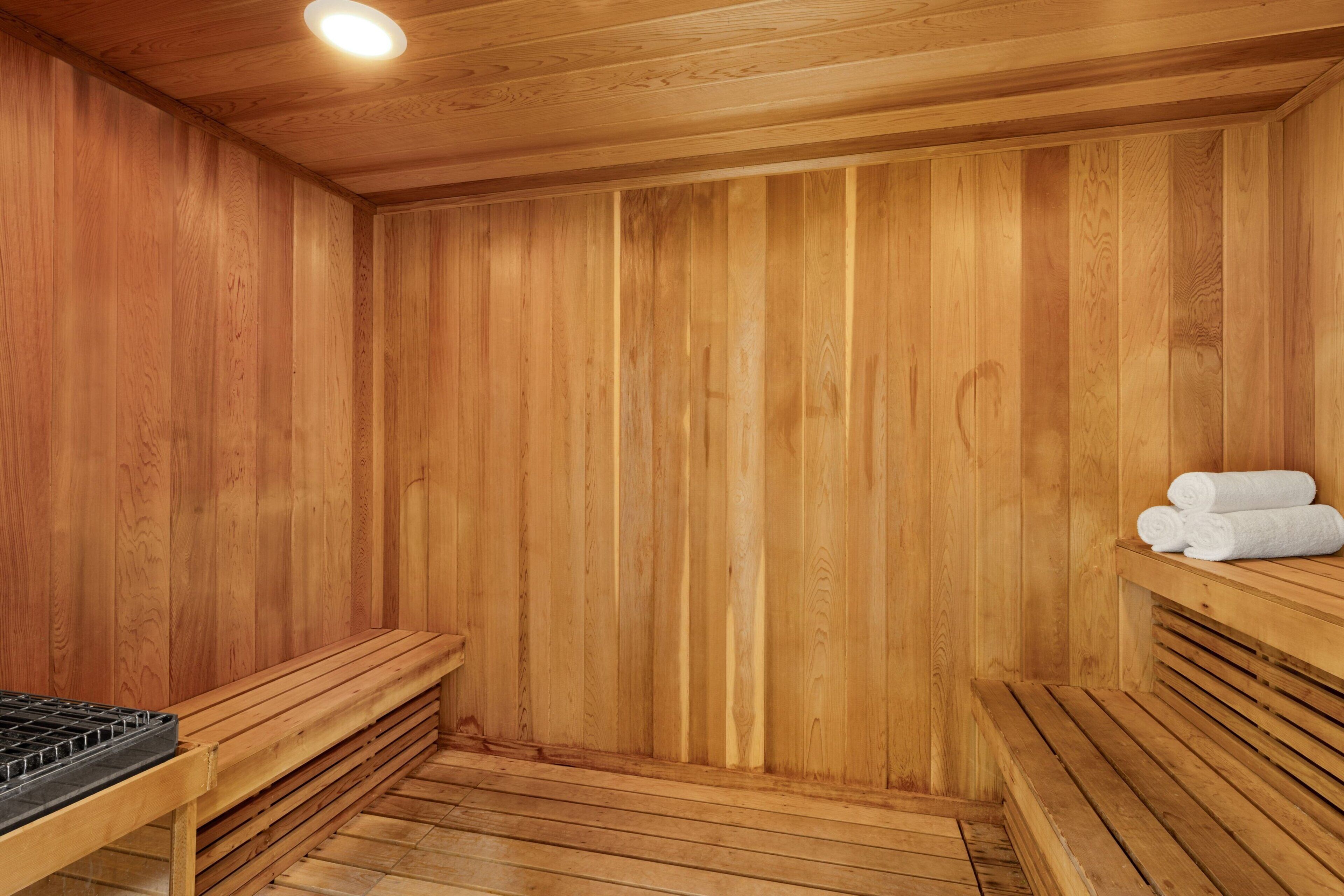 Una sauna de madera con bancos y un banco con un elemento calefactor.