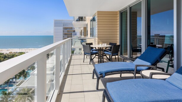Ein Balkon mit Blick auf den Strand, einen Pool und eine Essgegend mit Gartenmöbeln.