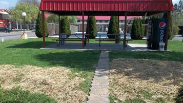 A red pavilion with benches, a stone pathway, and a Pepsi vending machine.