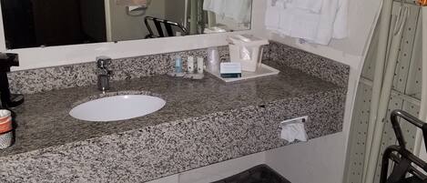 A bathroom with a granite countertop, a sink, a mirror, and a towel rack.