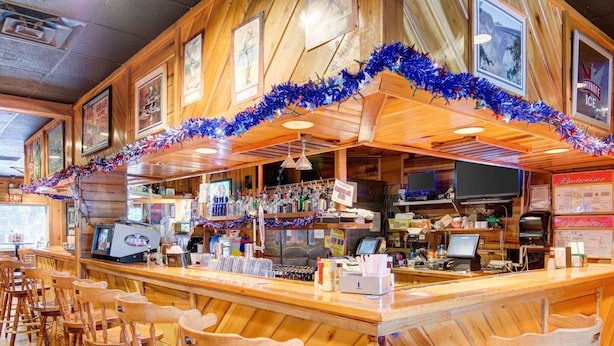 A bar area with wooden furniture, a counter with various items, and a festive garland.