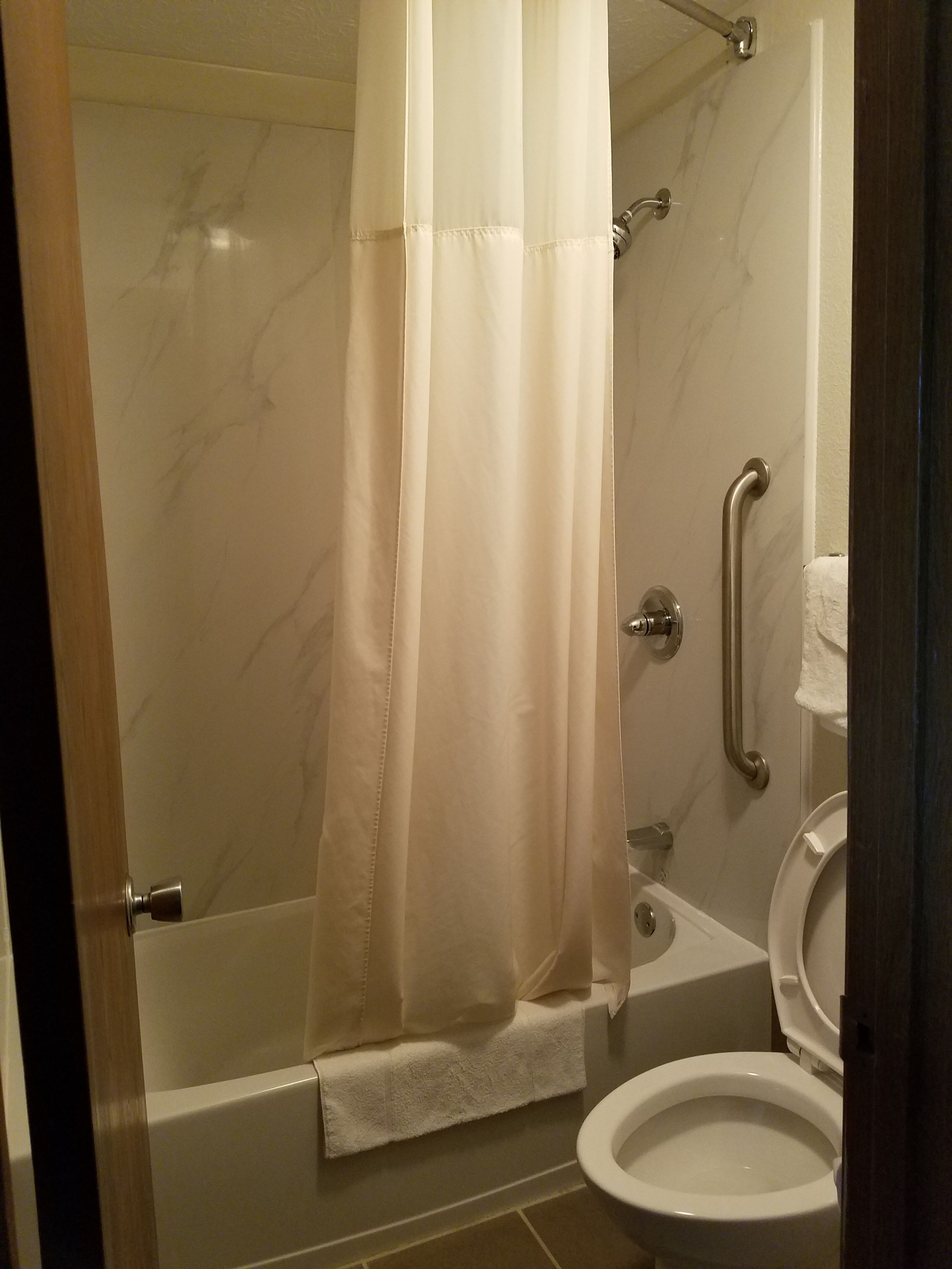 Een badkamer met douche, toilet en een greep.