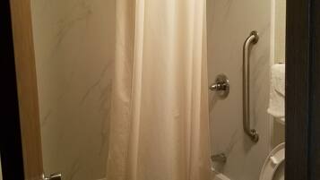 Een badkamer met douche, toilet en een greep.