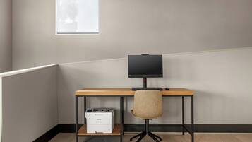 Un bureau d’angle équipé d’un bureau, d’une chaise, d’un écran, d’un clavier et d’une imprimante.
