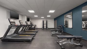 Un gimnasio con cintas de correr, elípticas y equipo de pesas.