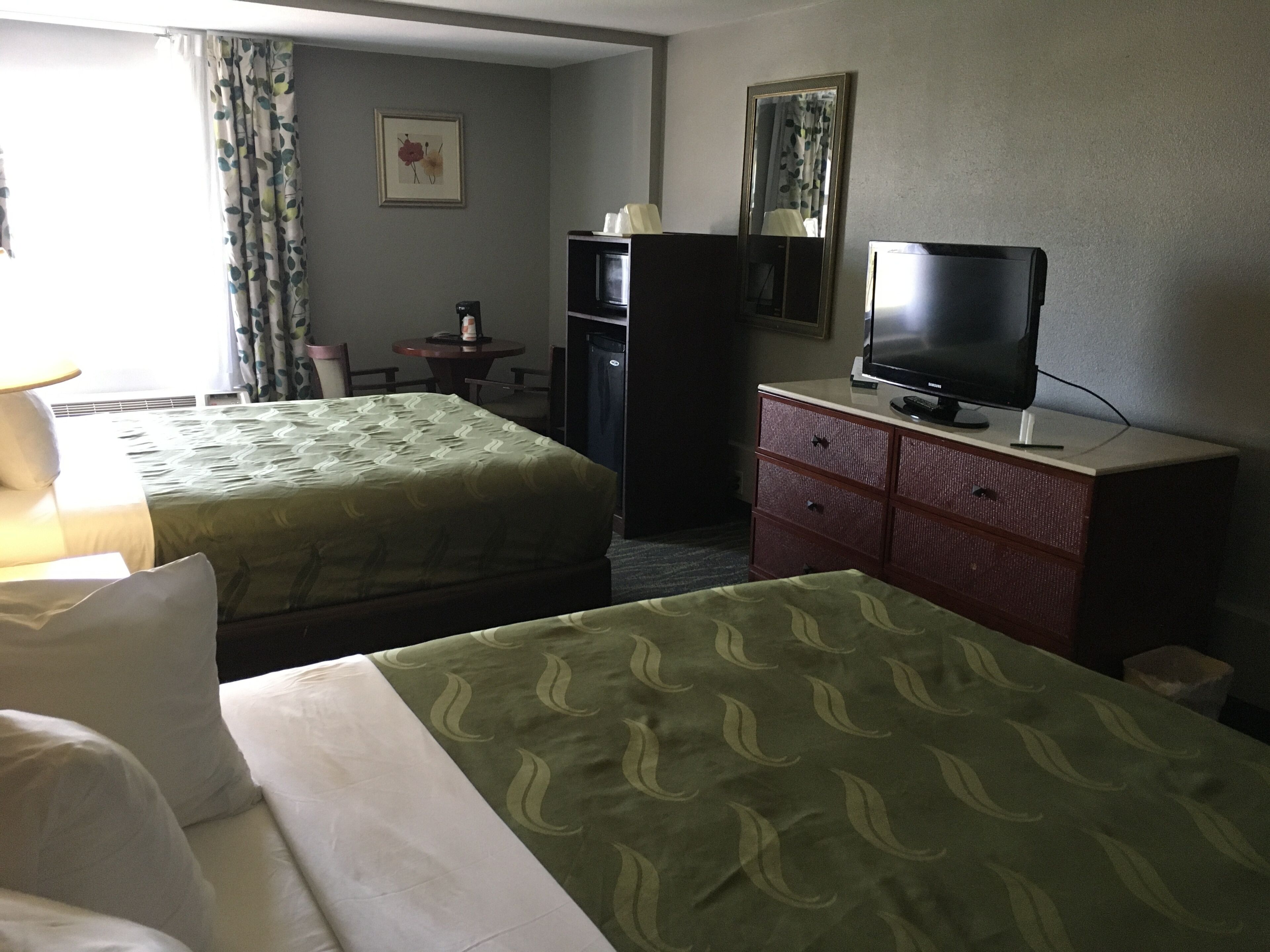 Habitació d'hotel amb dos llits, televisió, escriptori i armari.