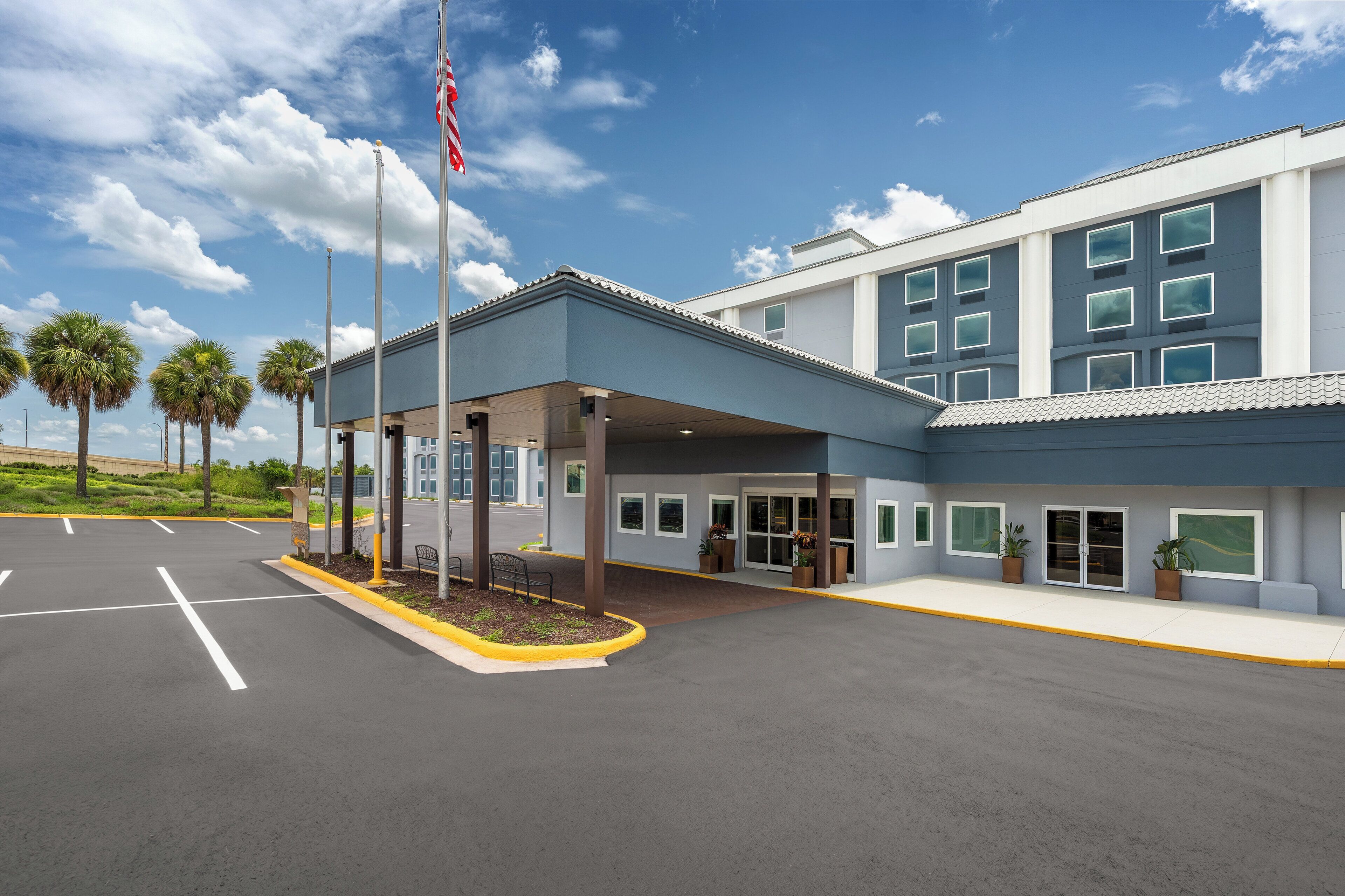A modern building with a covered entrance, multiple windows, and a flagpole with an American flag.