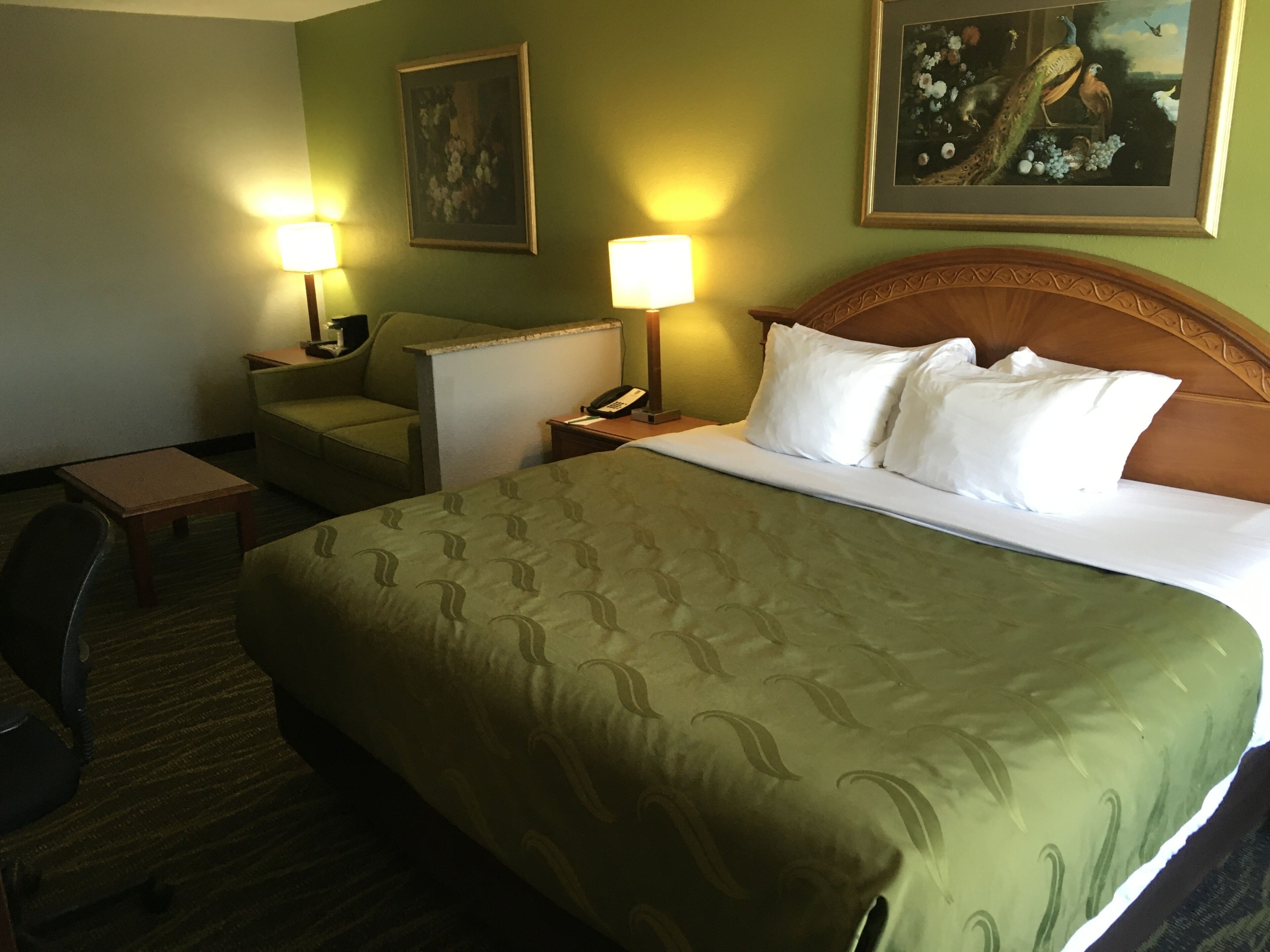 A hotel room with a large bed, two bedside tables, a chair, and two lamps.
