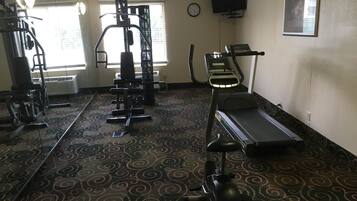 Un gimnasio con máquinas de cardio, equipo de pesas y una alfombra estampada.