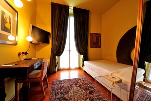 Une chambre d’hôtel avec un lit, un bureau, une chaise, une télévision et un tapis à motifs.