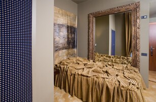 Una camera d'albergo con un letto grande, uno specchio e una parete decorata.