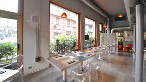 A modern dining area with a long table, clear chairs, and pendant lighting. - Art Hotel Boston (Turin)