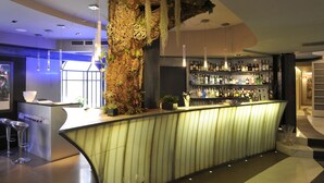 A modern bar area with a unique rock-like structure, a well-stocked liquor shelf, and contemporary bar stools. - Art Hotel Boston (Turin)