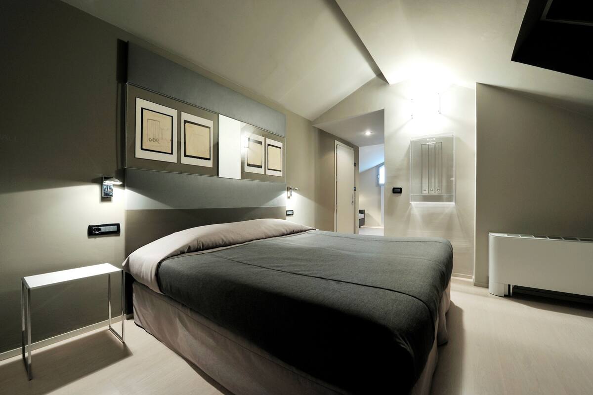 A modern bedroom with a large bed, bedside tables, and framed pictures on the wall.