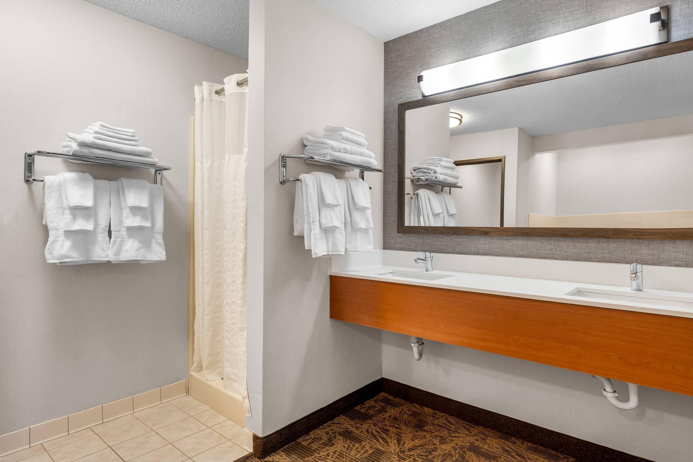 A bathroom with a white sink, a mirror, and two towel racks with folded towels.