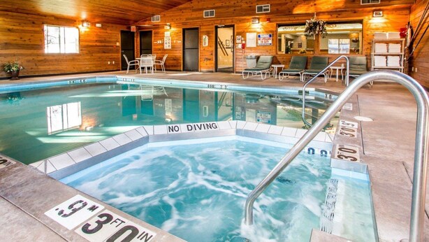 Una piscina interior amb parets de fusta i una zona de banyera hidromassatge.