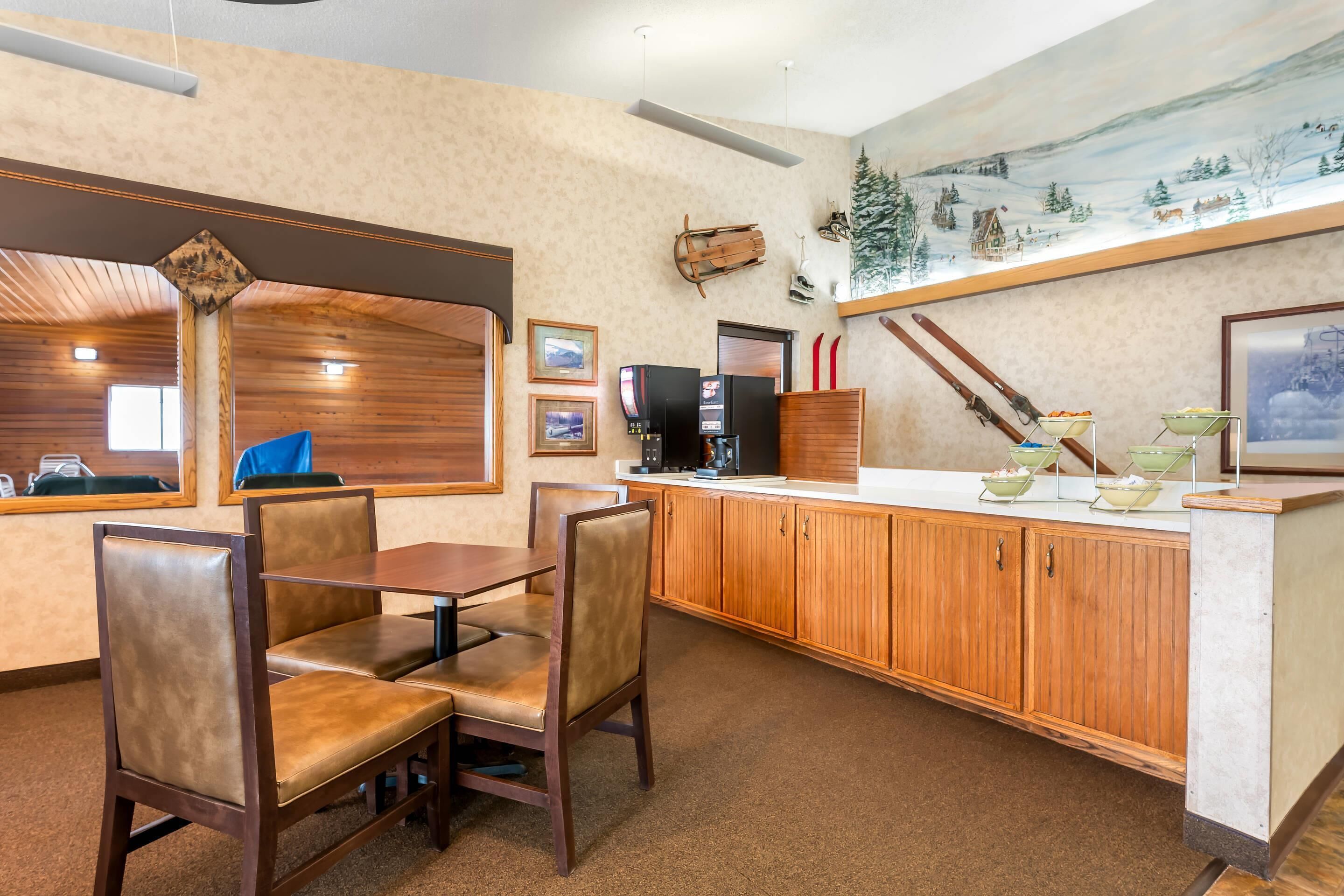 Un restaurante con mobiliario de madera, una barra con cuencos y un cuadro de un paisaje nevado.