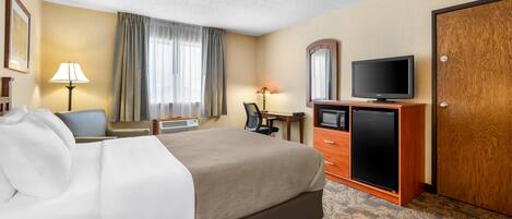 Una habitación de hotel con cama, escritorio, televisor y armario.