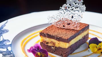 Un postre con una pieza metálica decorativa encima, servido en un plato con diseño floral.