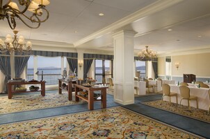 Un amplio vestíbulo de hotel con una gran vista al océano, un candelabro elegante y un comedor formal.