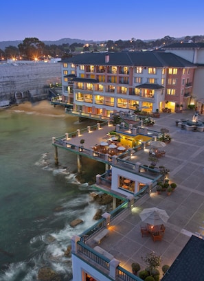 A hotel with multiple balconies overlooking a body of water, outdoor seating areas, and a well-lit entrance. - Monterey Plaza Hotel & Spa (Monterey)