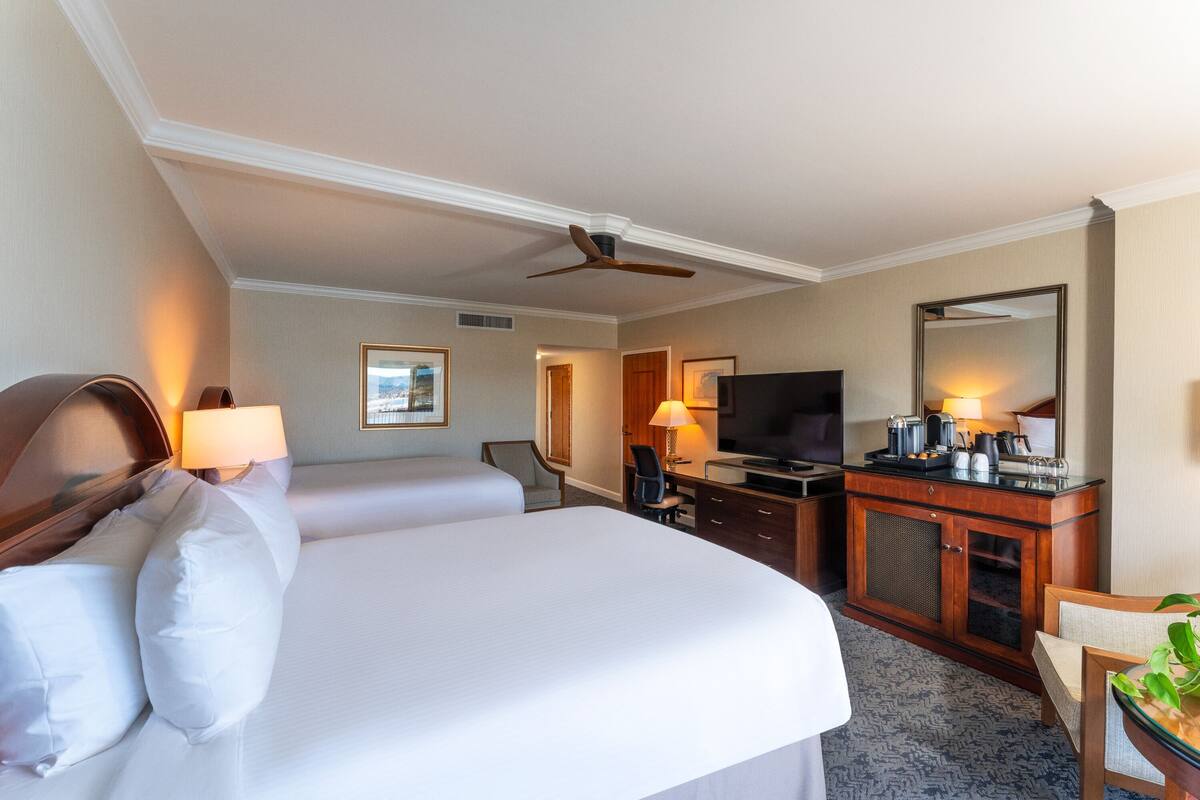 A hotel room with a large bed, a desk with a television, and a seating area with a chair and table.