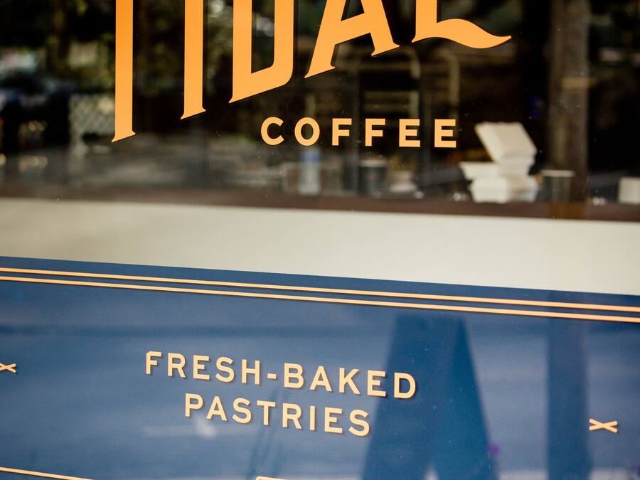 Skilt for Tidal Coffee med blå baggrund og gyldne bogstaver.