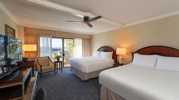 A hotel room with two beds, a desk with a chair, a TV, and a balcony with a view.