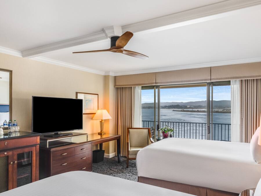 Une chambre d’hôtel avec deux lits, une télévision, un bureau avec une lampe et une vue sur l’eau.