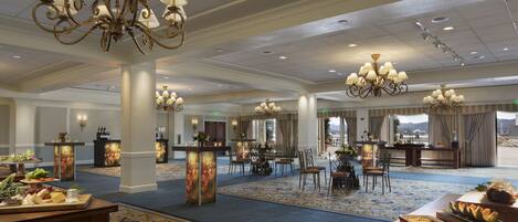 A spacious hotel lobby with multiple chandeliers, a reception desk, and a buffet area.